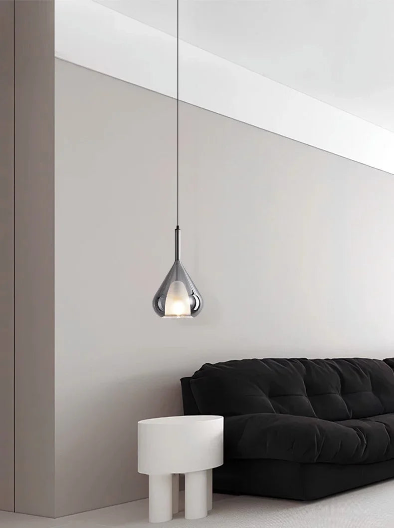 The teardrop hanging in a living room corner above a black sofa and stool