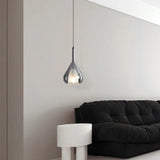 The teardrop lit on a long cord beside a black sofa and a pale side table