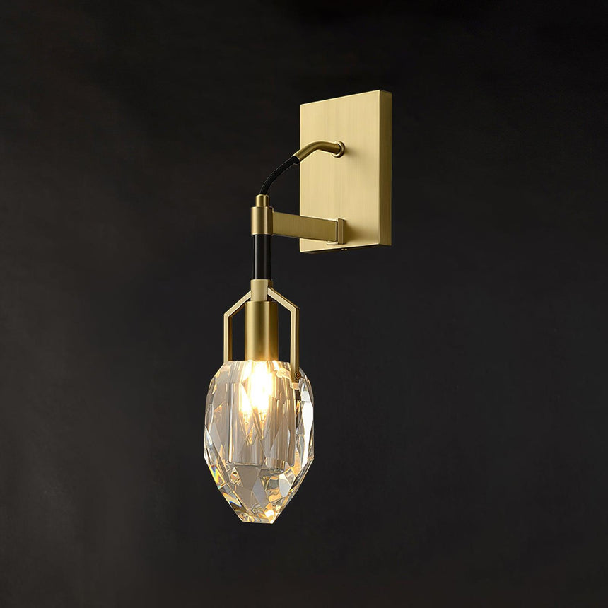 The crystal drop lit on a charcoal wall below the brass plate