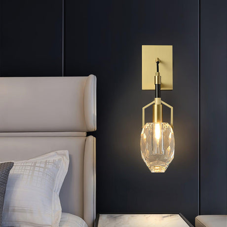The crystal drop lit on a dark wall beside a white upholstered headboard