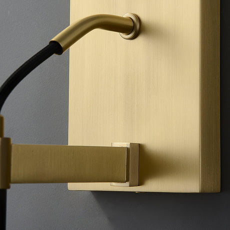 Close view of the brushed brass wall plate, the arm and the black cord