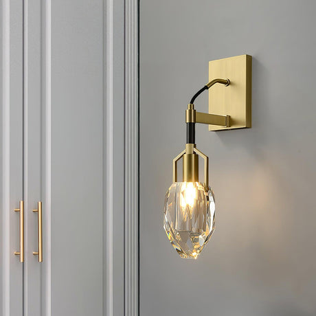 The crystal drop lit on a gray wall beside a wardrobe door with a brass handle
