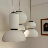 Three textured pendants of different heights in a pale room