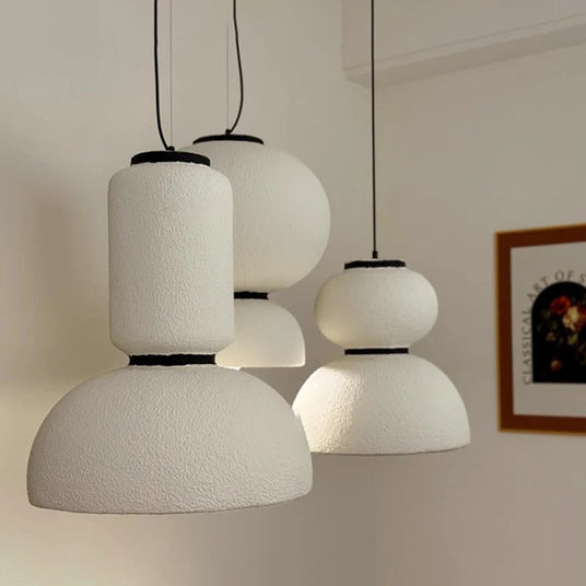 Three textured pendants of different heights in a pale room
