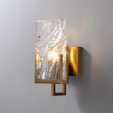 The sconce lit on a gray wall, light passing through the rippled glass
