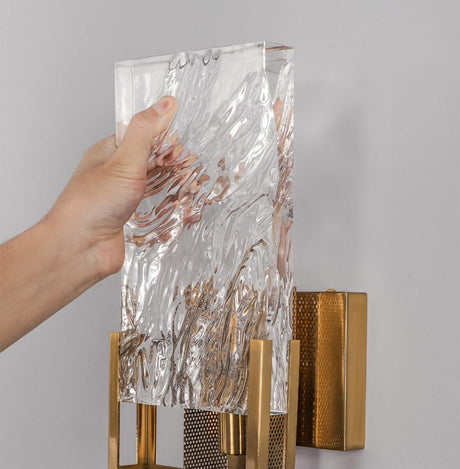 A hand holding the glass panel as it slides into the brass frame