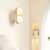 Sconce lit on a bedroom wall beside an arched alcove and a pale headboard