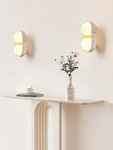 Two sconces lit either side of a console with flowers in an entry corner