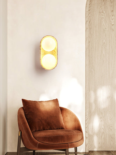 Sconce lit above a rust armchair with a cushion beside a slatted wood wall