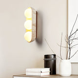 Sconce lit above a sideboard with books, a canister and a vase of branches