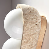 The carved travertine lip curving over the top of a white glass orb