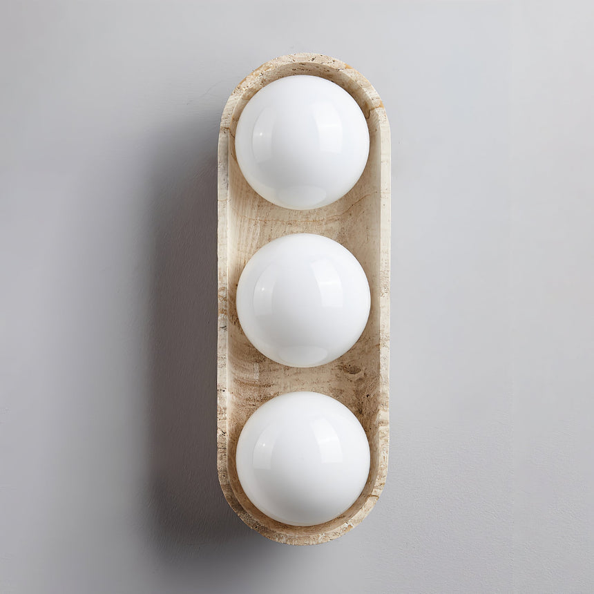Three white glass orbs sitting unlit in the stone shell on a gray ground