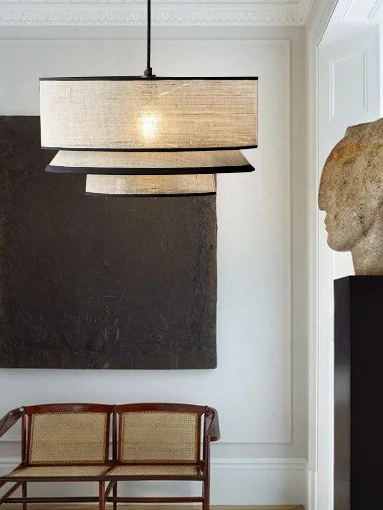Tiered drum pendant light lit in a dark interior with dining chairs
