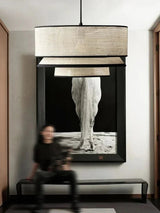 Tiered drum pendant light in a hallway above a bench and framed artwork