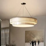 Tiered drum pendant light lit in a tall living room beside framed artwork