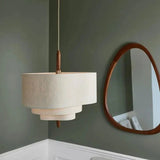 Two tier drum shade hung next to a round wall mirror