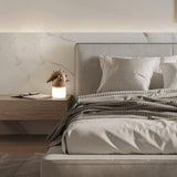 Touch control bedside lamp lit on a nightstand beside a made bed
