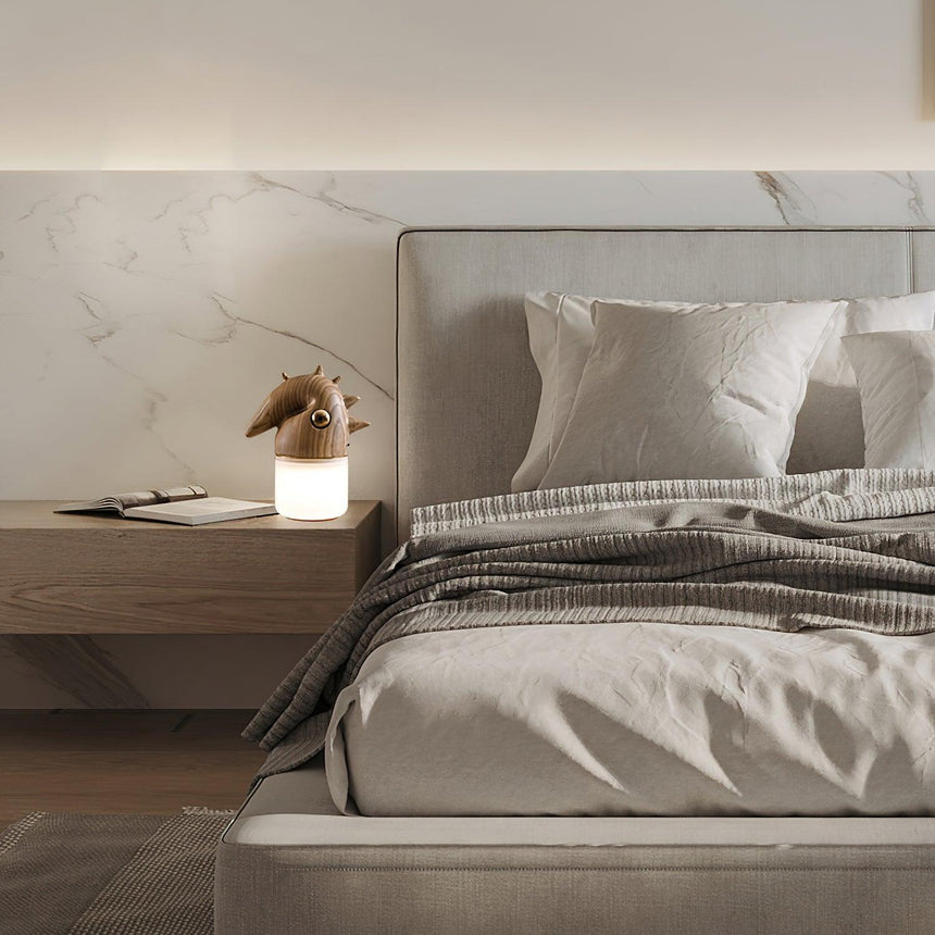 Touch control bedside lamp lit on a nightstand beside a made bed