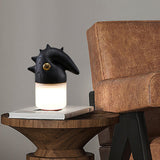 Touch control bedside lamp lit on books beside a leather armchair