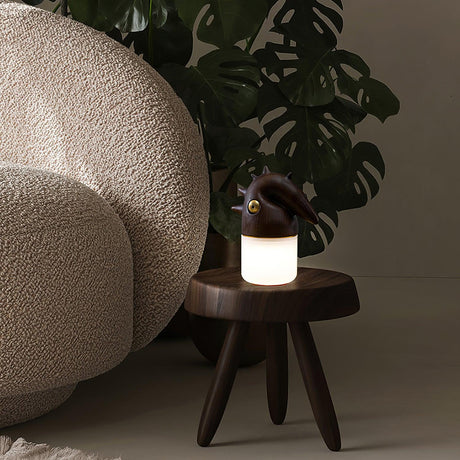 Touch control bedside lamp lit on a stool beside a large plant