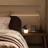 Touch control bedside lamp lit on a nightstand in a warm bedroom