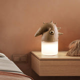 Touch control bedside lamp lit on a wooden nightstand beside a bed