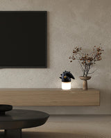 Touch control bedside lamp lit on a sideboard below a screen