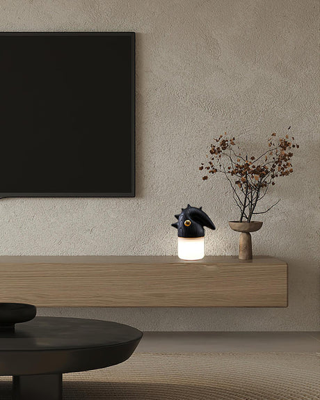 Touch control bedside lamp lit on a sideboard below a screen