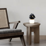 Touch control bedside lamp lit on a wooden stool beside a cane chair