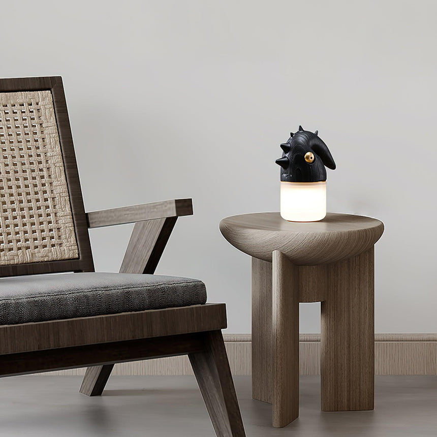 Touch control bedside lamp lit on a wooden stool beside a cane chair