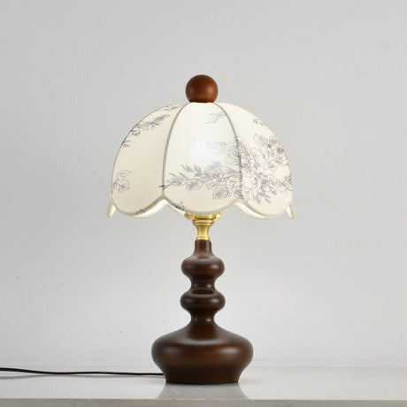 Scalloped toile shade lamp lit against a pale wall