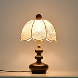 Scalloped toile shade lamp lit warm, the panels glowing evenly