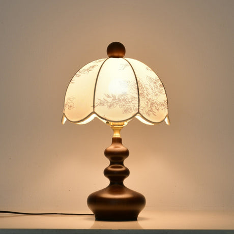 Scalloped toile shade lamp lit warm, the panels glowing evenly