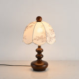 Toile shade lamp lit with a warm bulb, the scalloped hem in shadow
