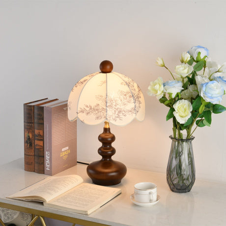 Toile shade lamp lit beside white roses and a stack of bound books