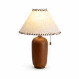 Traditional table lamp with a woven shade bound in leather, lit