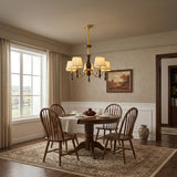 Chandelier lit above a round table with spindle chairs around it