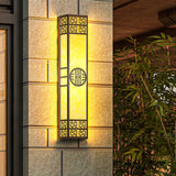 The light lit on a stone tile wall beside a doorway, bamboo leaves at the edge