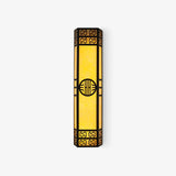 Tall black outdoor wall light with fretwork ends, a round medallion and glowing amber panels