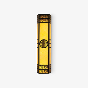 Tall black outdoor wall light with fretwork ends, a round medallion and glowing amber panels