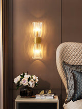 The sconce beside a quilted armchair above a side table with flowers