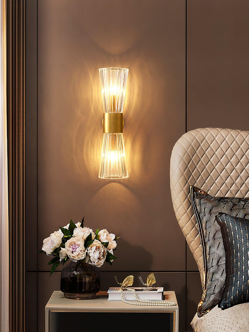 The sconce beside a quilted armchair above a side table with flowers