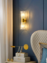 The sconce on a blue wall above a desk with a lamp beside a quilted chair