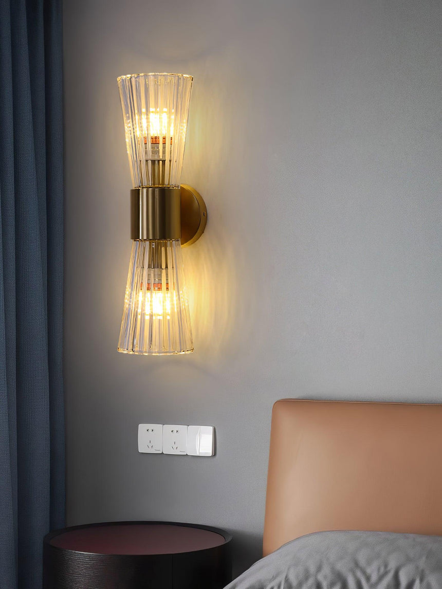 The sconce lit on a gray wall beside a leather headboard