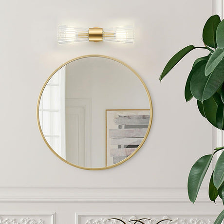 The sconce mounted sideways above a round gold mirror on a white paneled wall