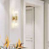 The sconce lit on a white paneled wall above a vase of bird of paradise flowers