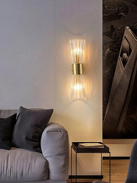 The sconce lit above a gray sofa and a small side table