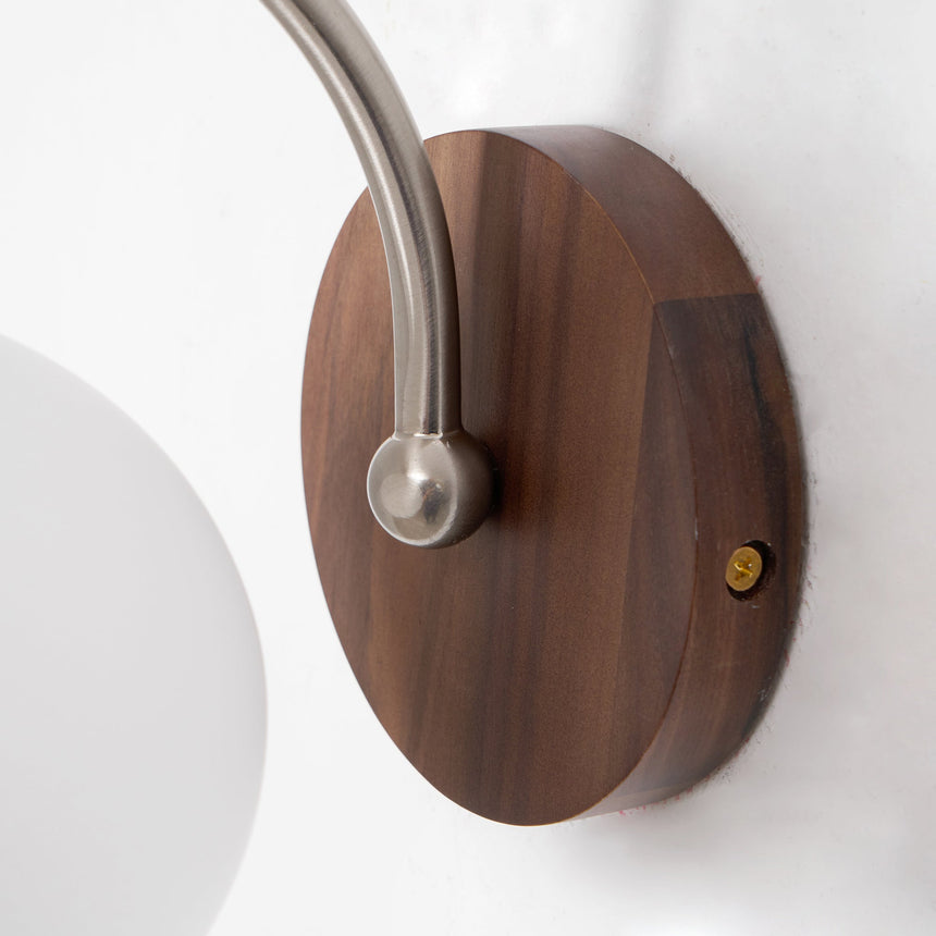 The round walnut backplate with the chrome arm curving away from it