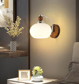 Sconce lit above a nightstand with a framed photo and a small plant