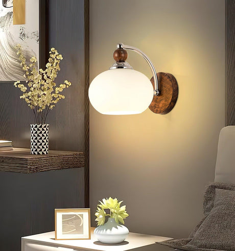 Sconce lit above a nightstand with a framed photo and a small plant